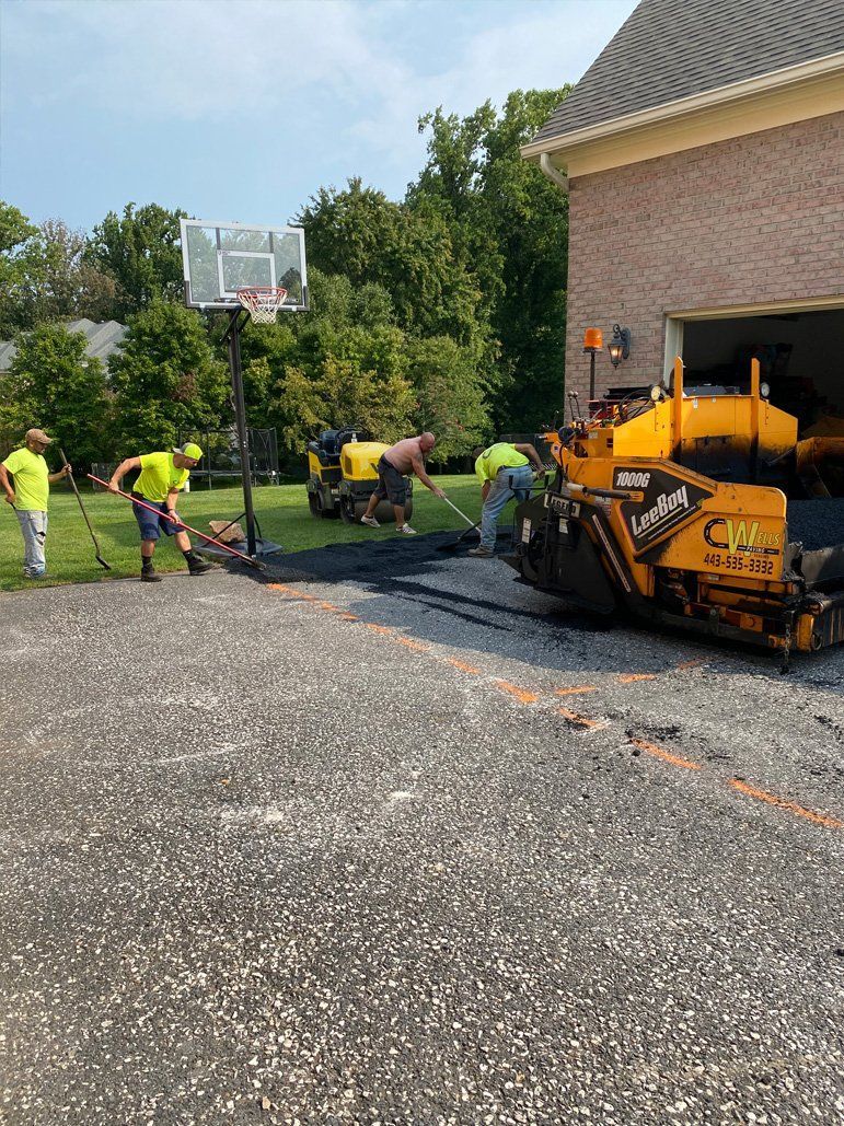 A group of men are working on a driveway in front of a garage.