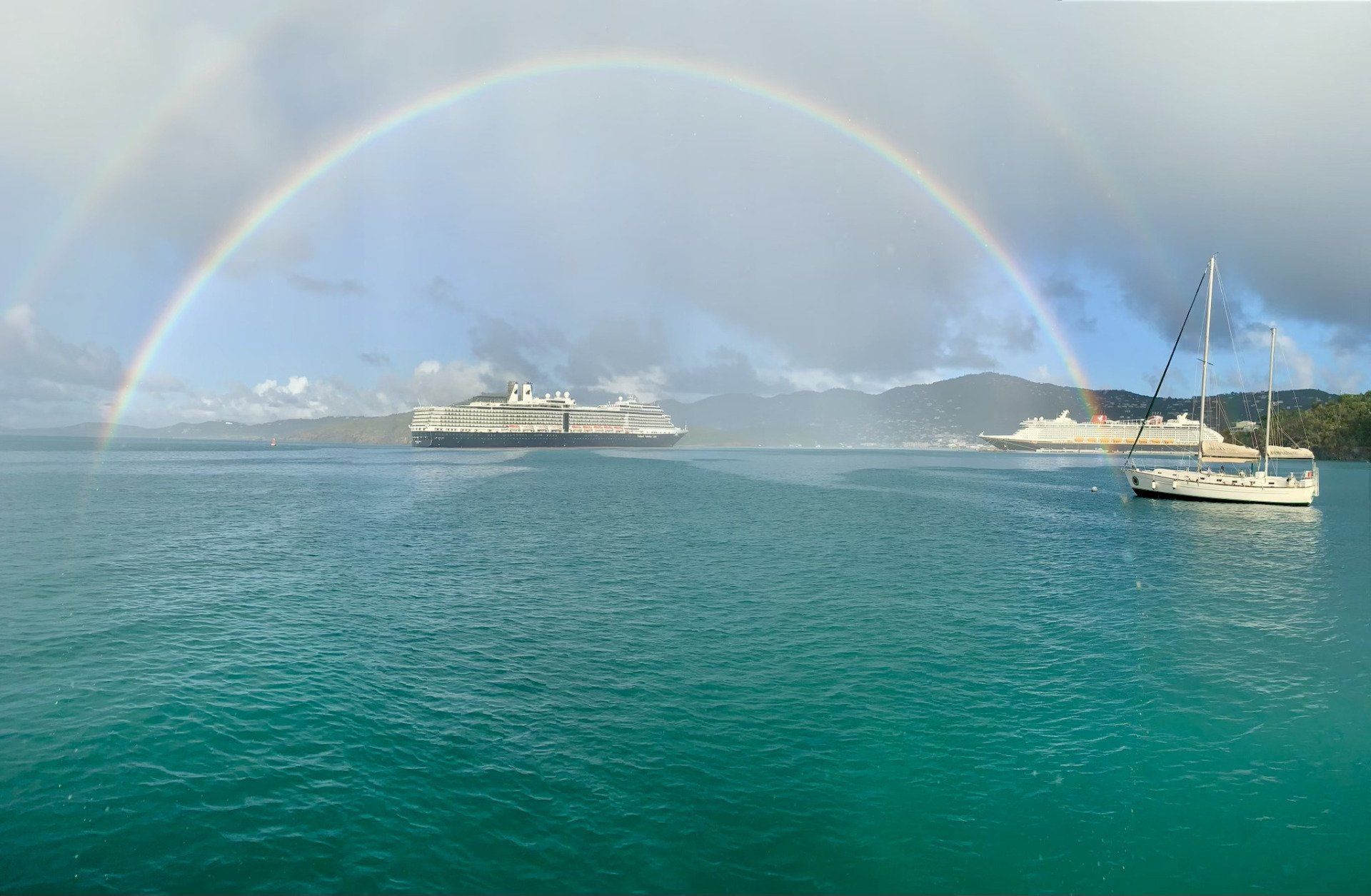 Boat in the middle of the ocean with rainbow in behind