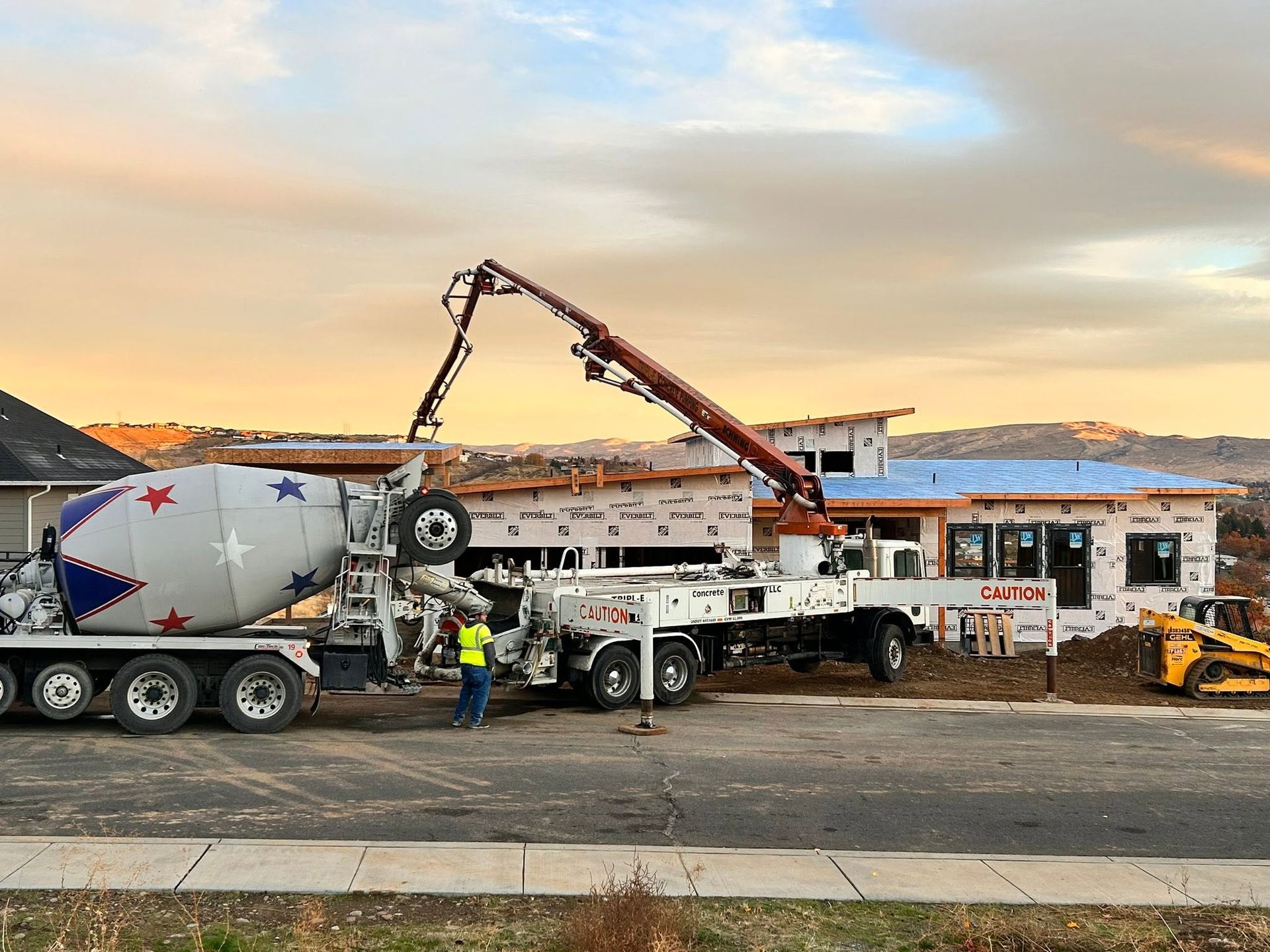 Concrete truck pouring at a construction site with workers and a crane at sunset