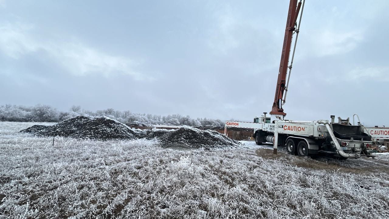 Red crane truck at a snowy construction site under an overcast sky