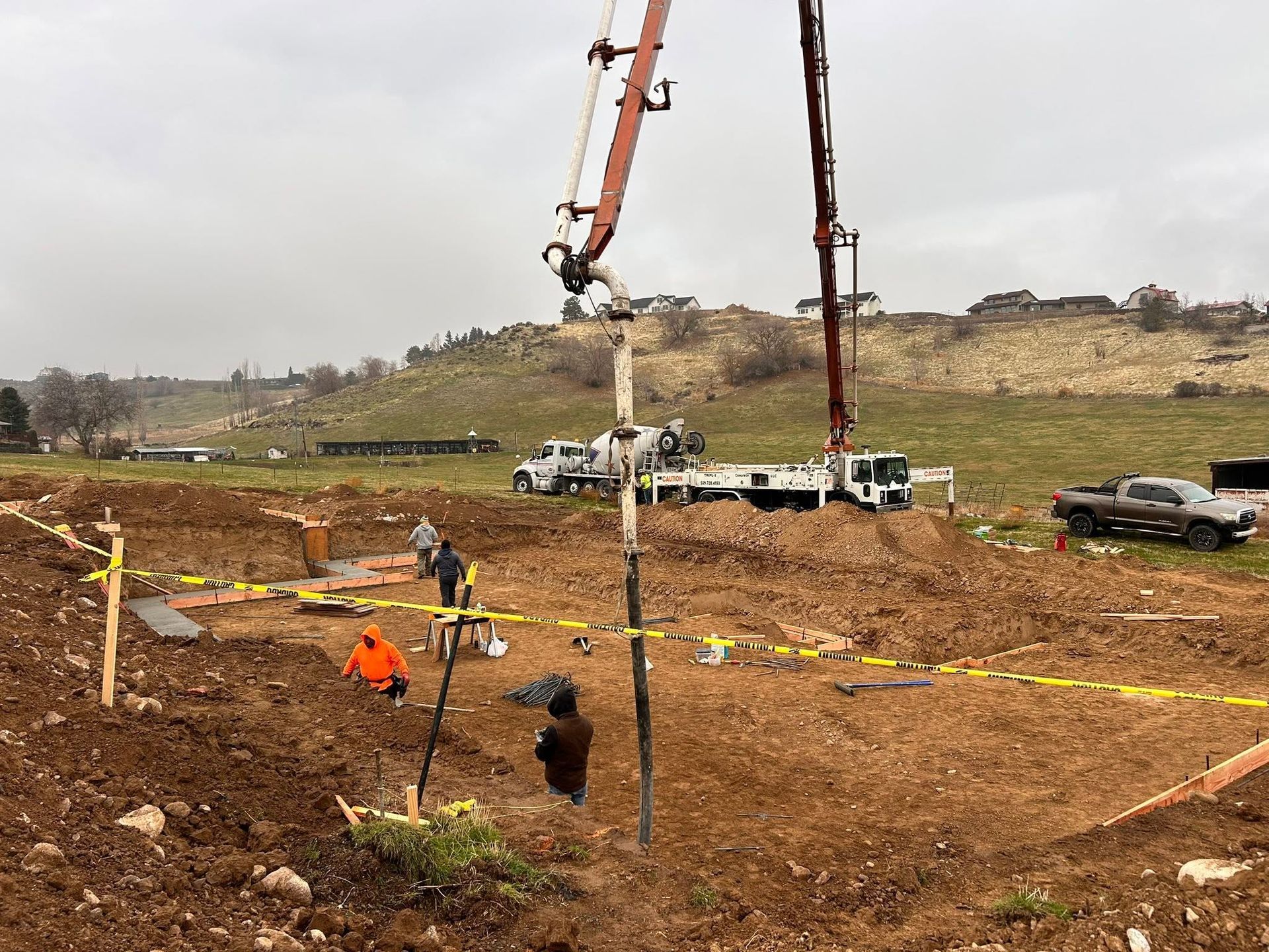 Construction site with concrete pump trucks pouring a foundation in a dirt excavation area
