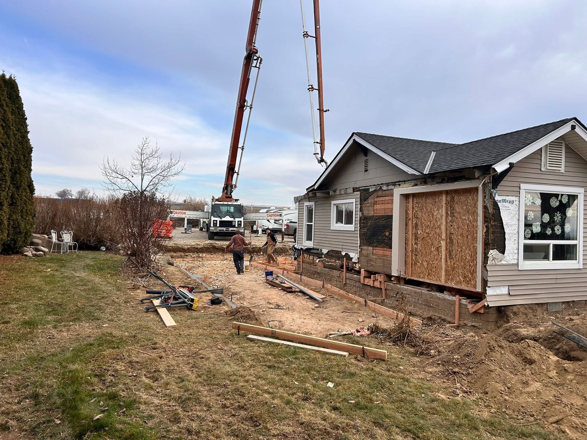 House demolition with crane and excavator beside a damaged home in a suburban yard