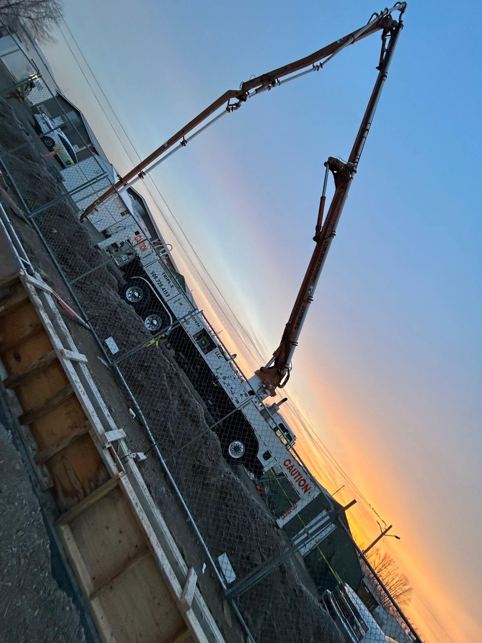 Concrete pump truck pouring at a construction site at sunset