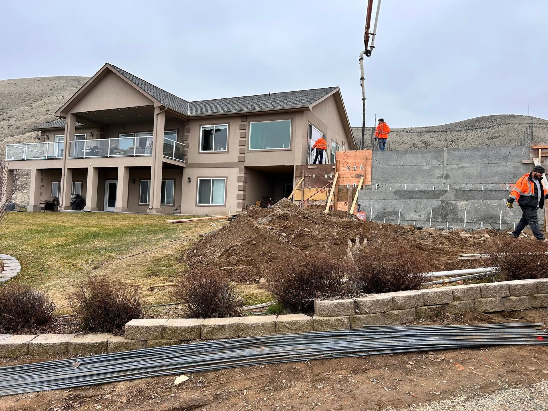 Workers installing a zipline beside a two-story house under construction on a rocky hillside