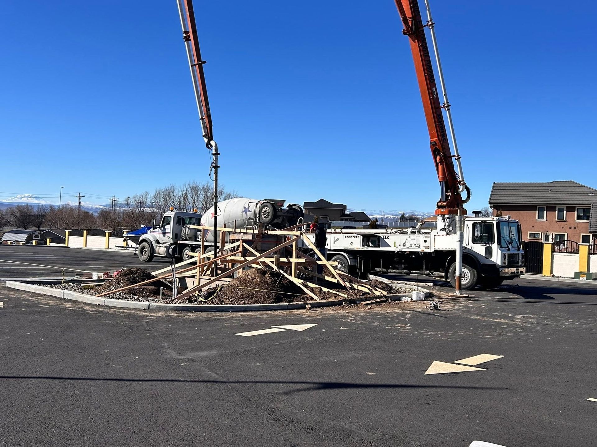 Crashed vehicle and debris on roadway, with two red cranes lifting wreckage near a building