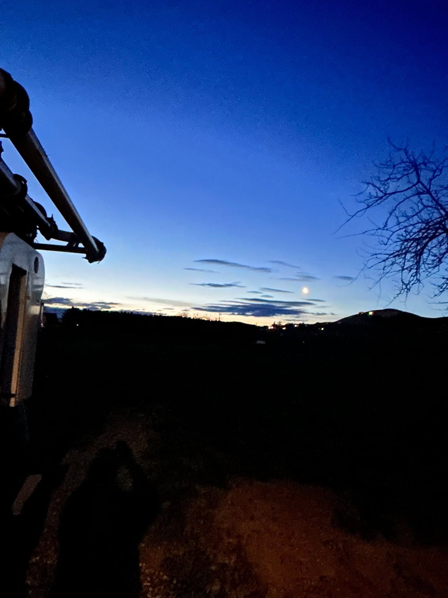 Twilight sky over dark hills, with a bicycle handlebar silhouetted on the left.