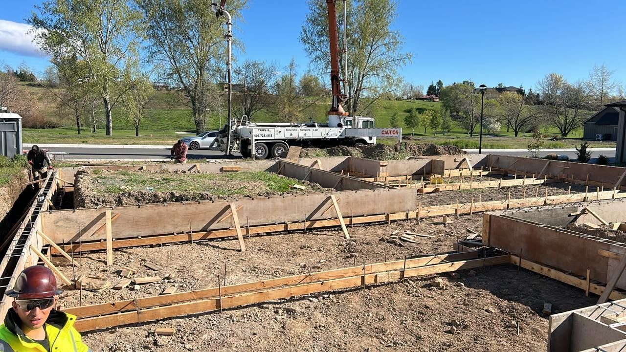 Construction site with foundation forms, rebar, and workers in hard hats under a sunny sky
