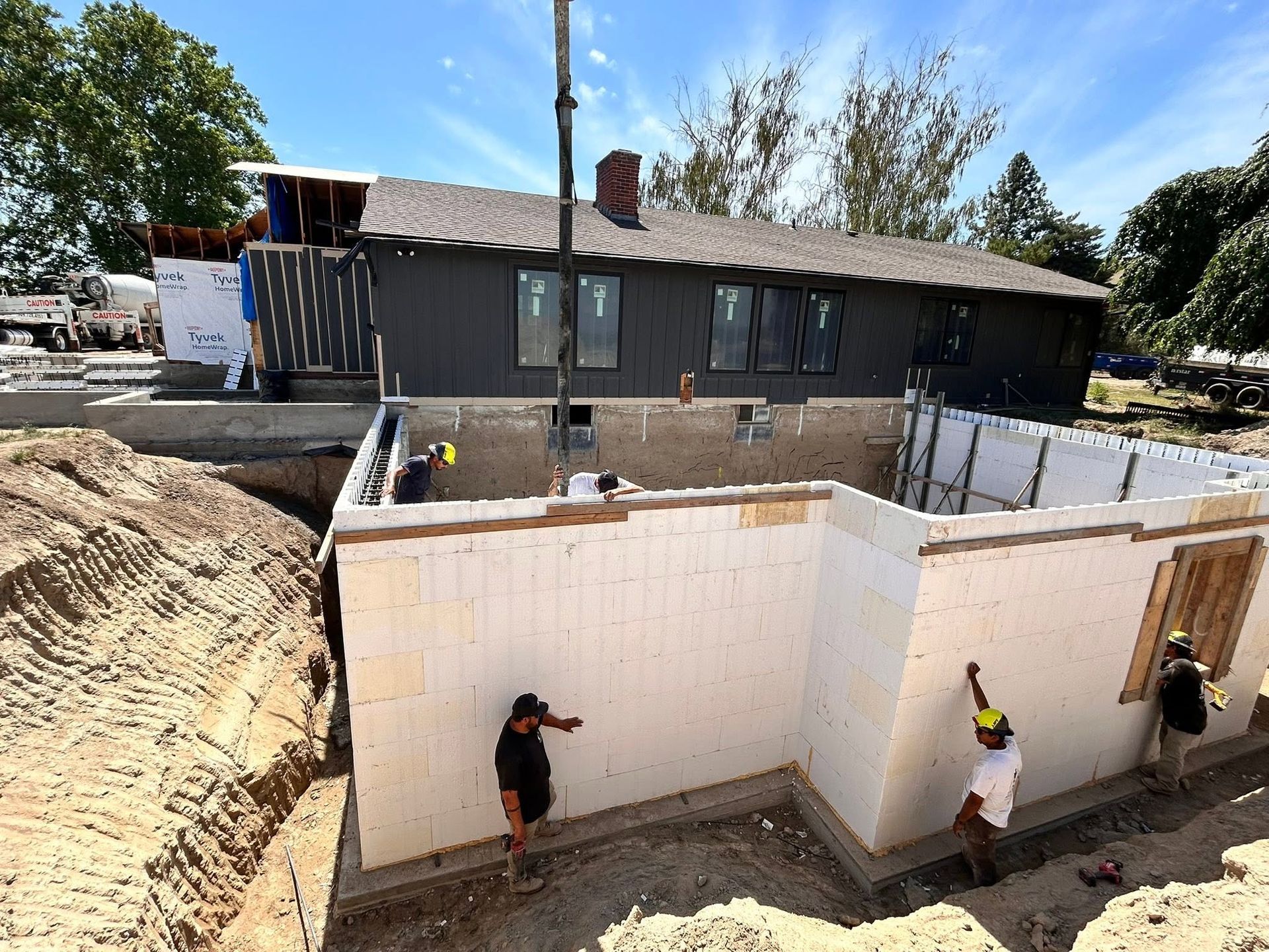 Workers waterproofing a basement foundation at a house construction site
