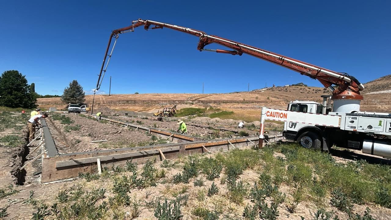 Concrete pump truck pouring on a construction site under a clear blue sky