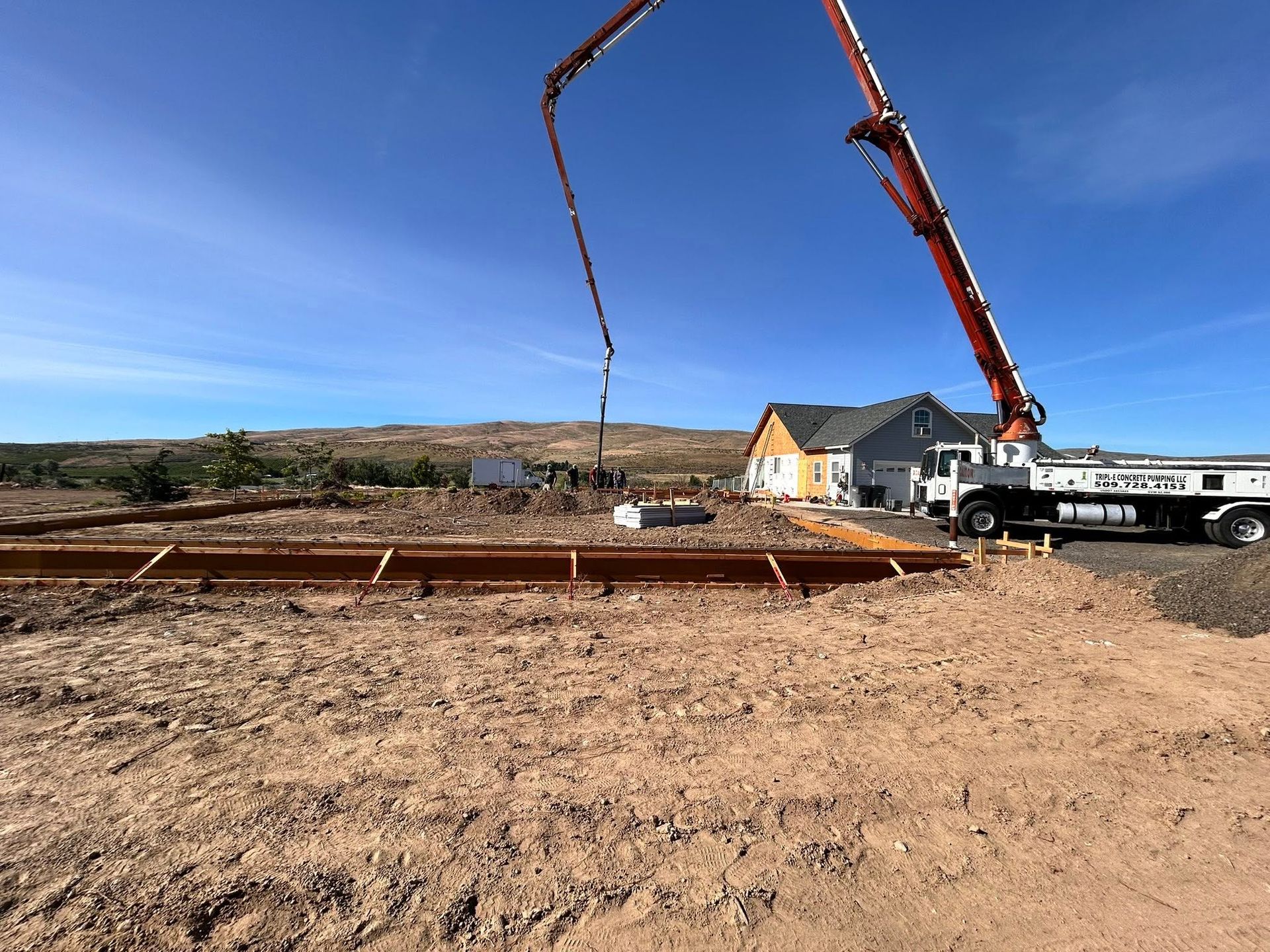 Concrete pump truck pouring concrete at a construction site under a clear blue sky