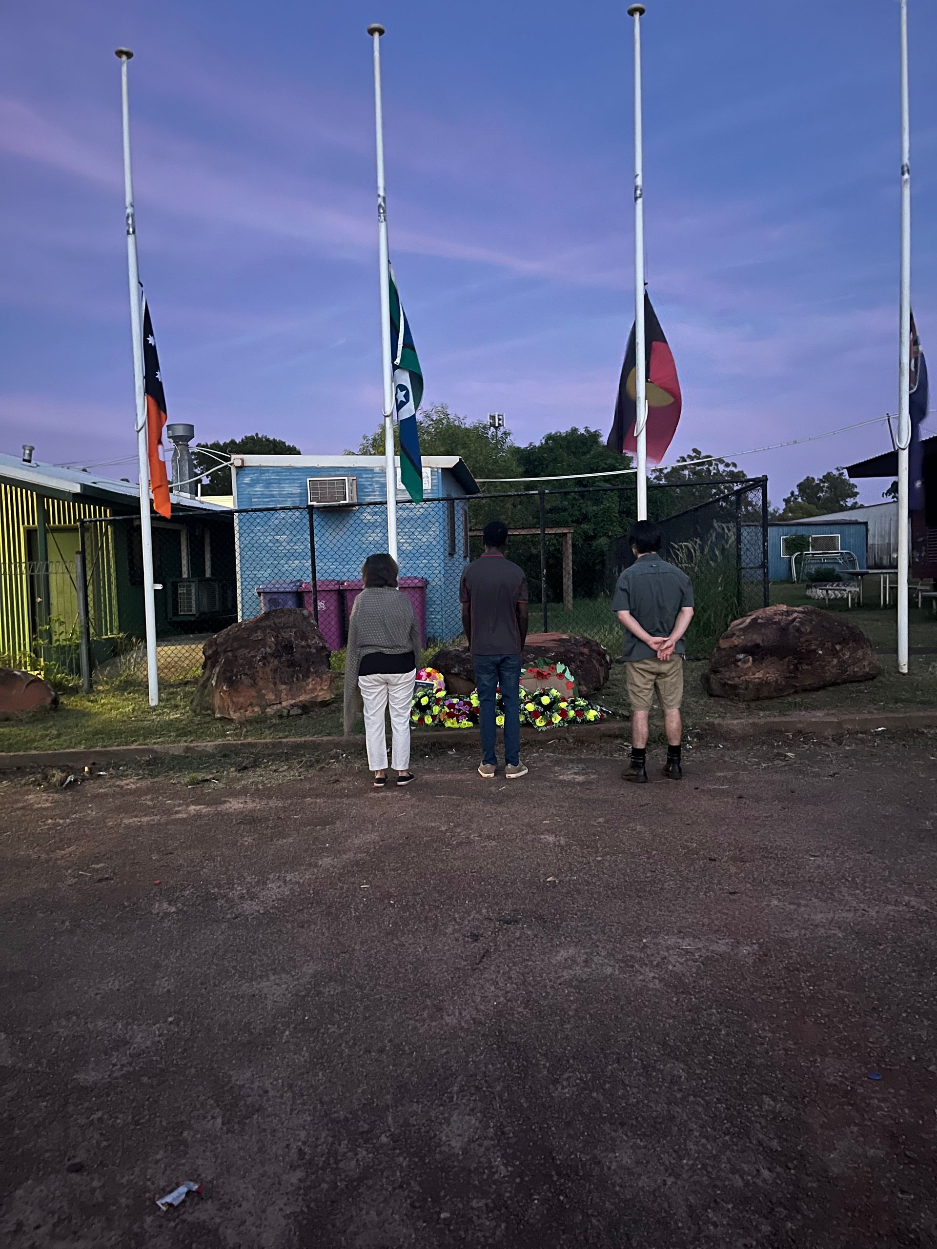 Three people lay wreaths