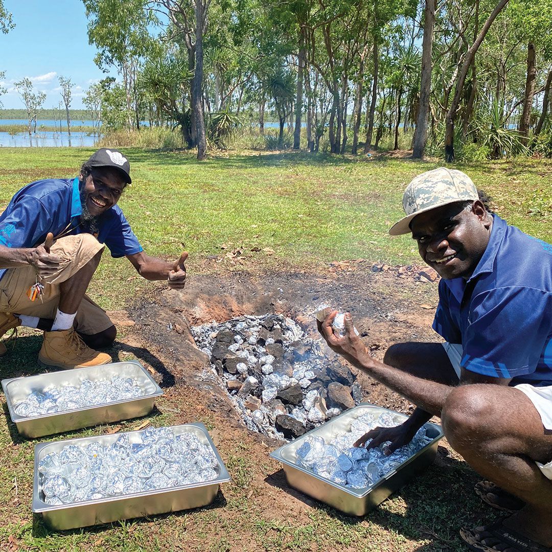 Two men cooking on an open fire.