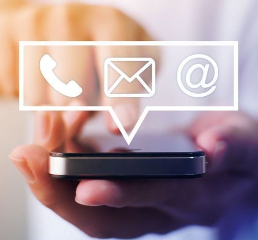 Mano che tiene un telefono con le icone dei contatti: telefono, e-mail e simbolo chiocciola.