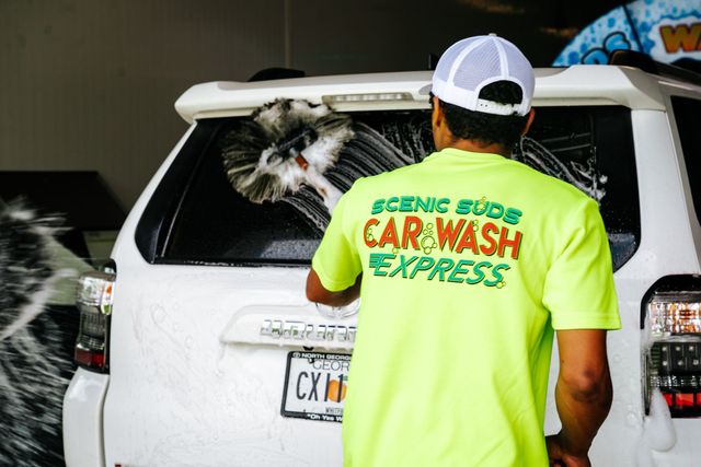 A man in a neon green shirt is washing a car.