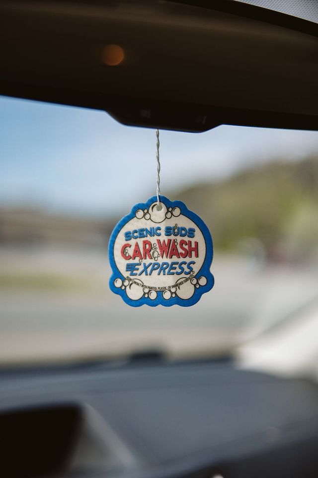A car air freshener is hanging from the rear view mirror of a car.