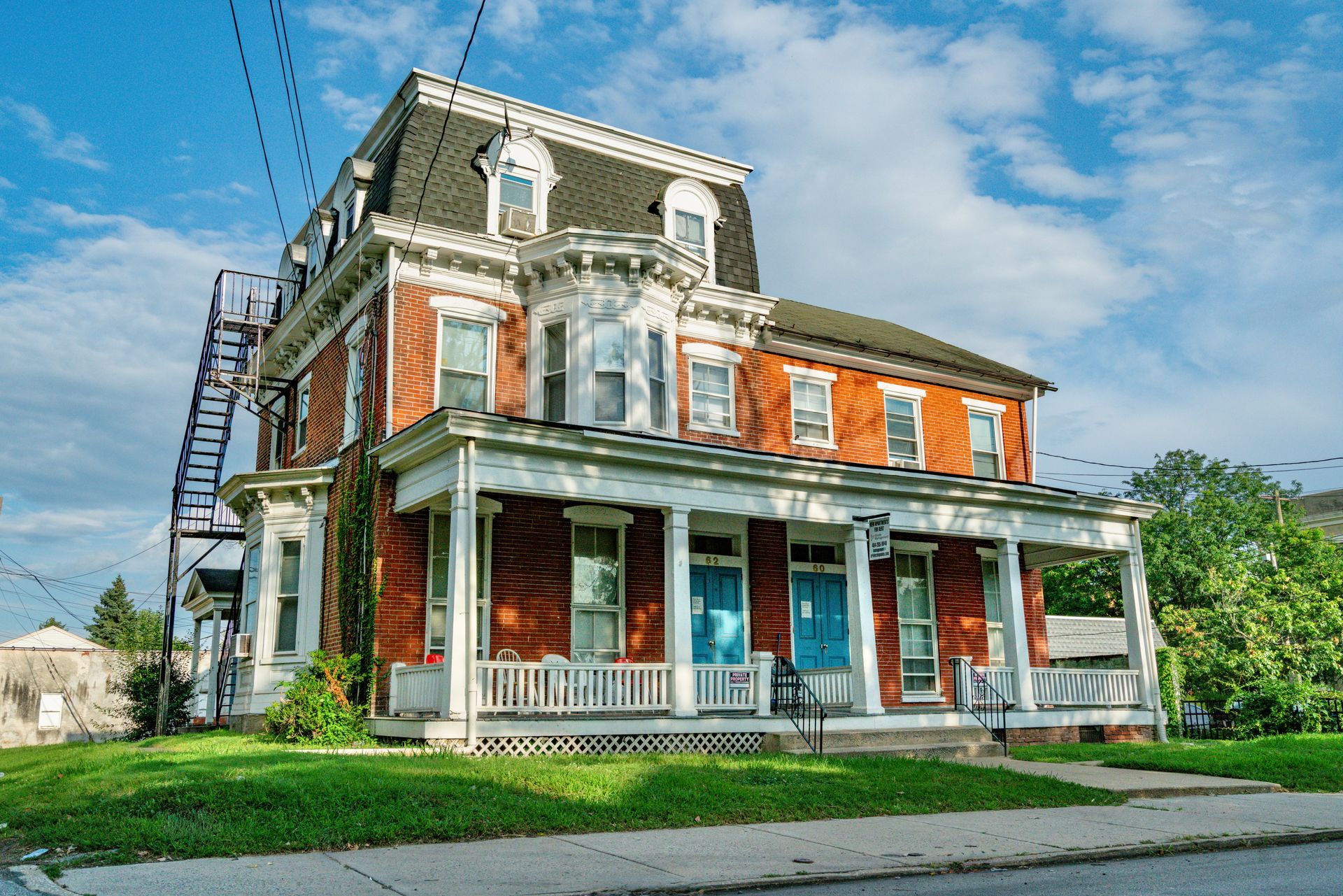 Front facing photo of an old home, 3 stories with red brick and black and white features