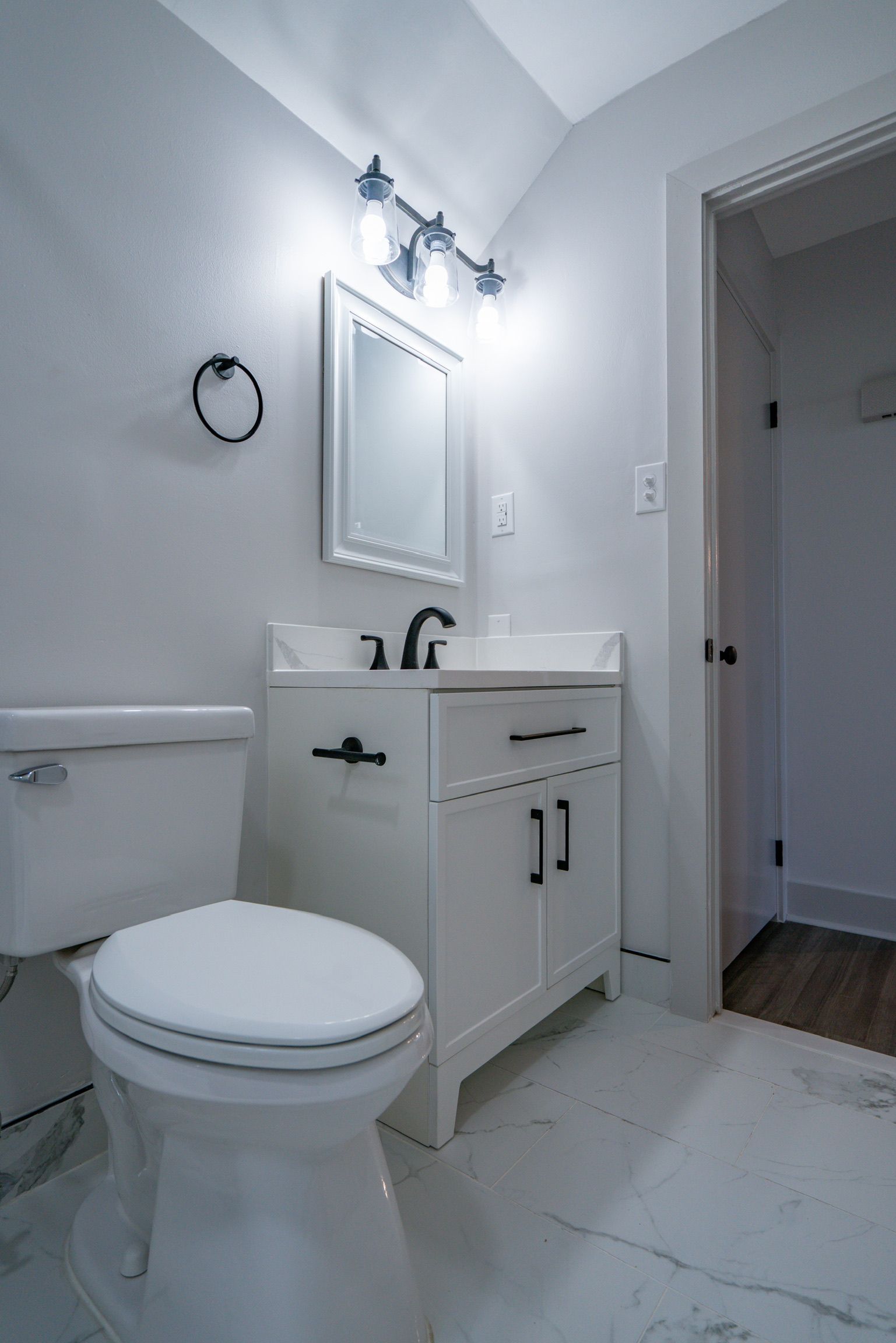 Photo of a white bathroom with a toilet and a sink and vanity mirror