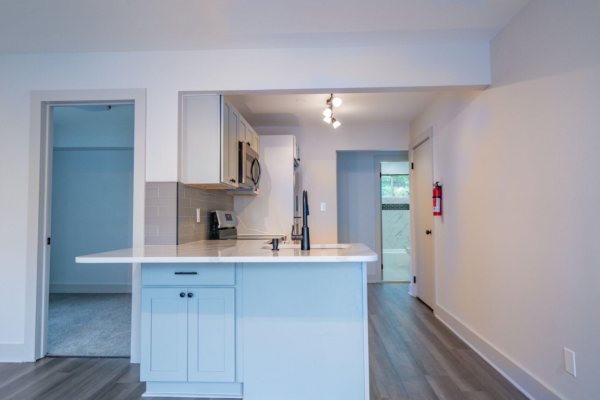 Photo of a white kitchen with a hallway in the background