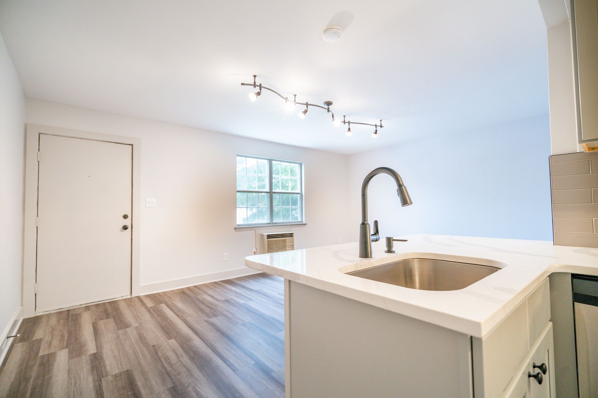 Photo showing a sink in the kitchen, with the living room in the background