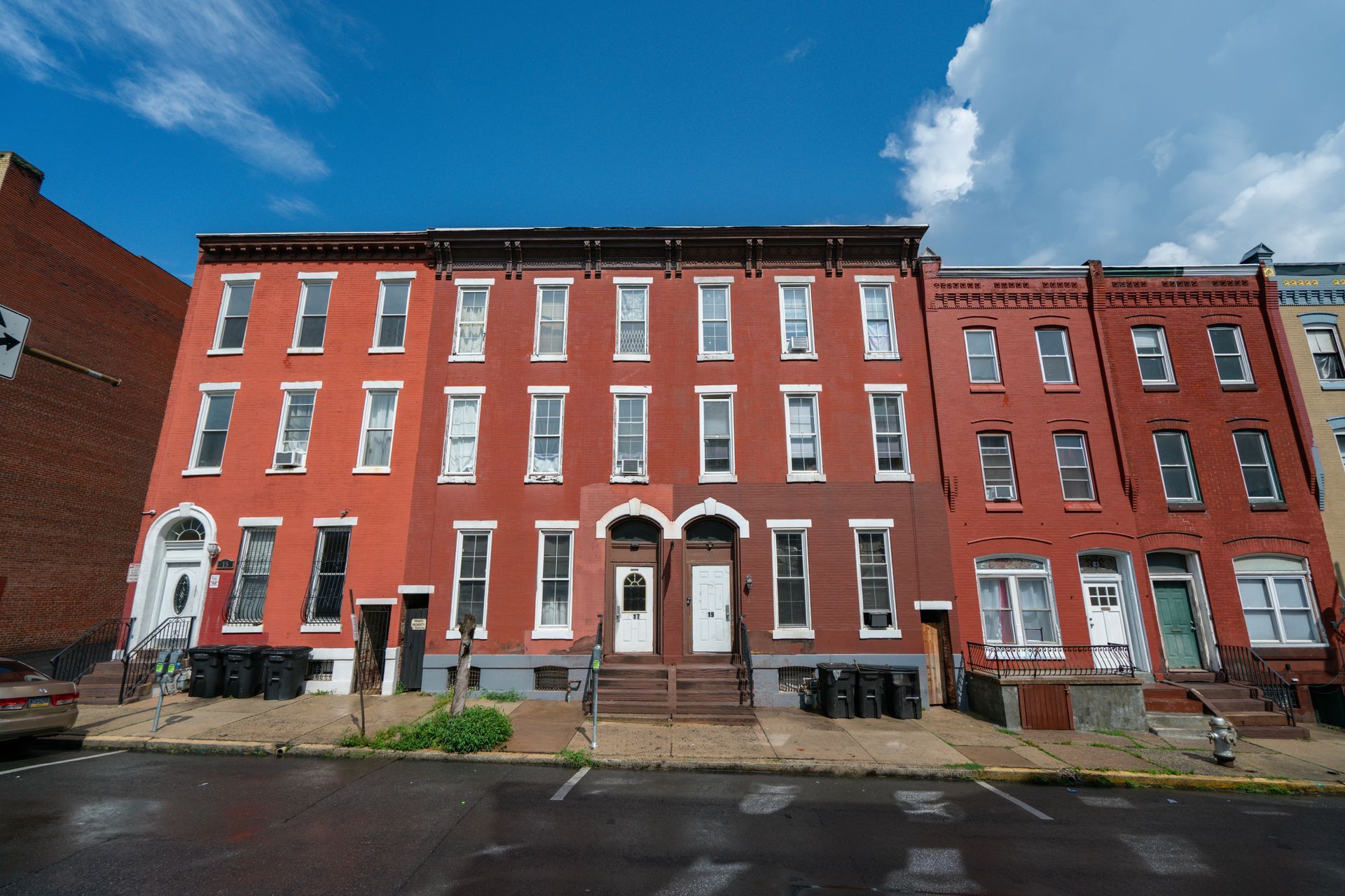 Photo of a large, 3 story red brick building showing the neighboring buildings 