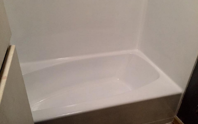 A clean, white bathtub and shower surround set in a bathroom corner.