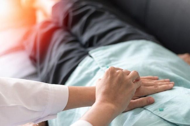 Un médico examina el estómago de un paciente mientras está acostado en un sofá.