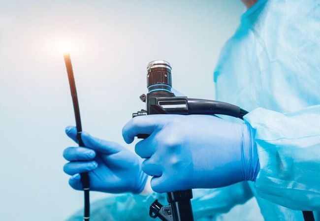 Un cirujano sostiene un endoscopio en sus manos.