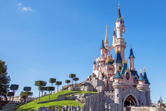 Castello della Bella Addormentata a Disneyland Paris, guglie rosa e blu contro un cielo azzurro.