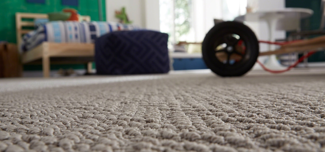 Low-angle view of a carpeted room with a black wheel and blurred furniture in the background