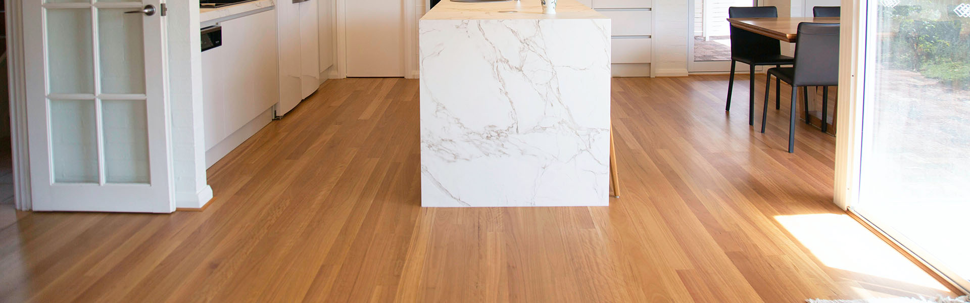 Bright kitchen with light wood floors and a white marble island in the center.