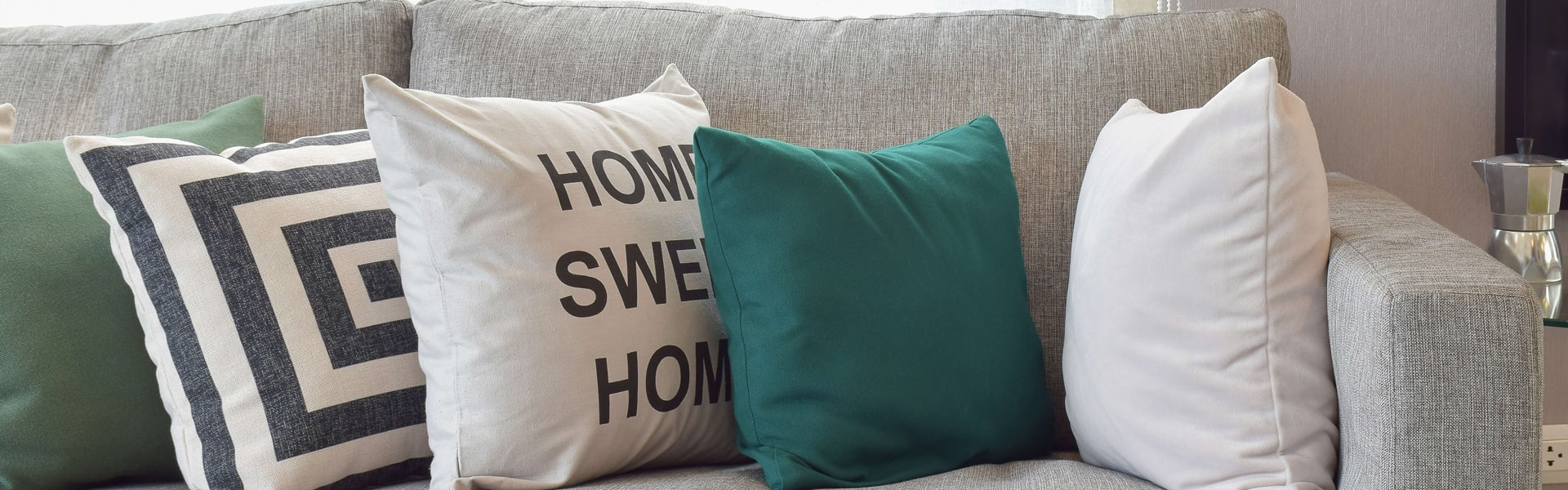 Cozy sofa with patterned, teal, and white throw pillows, including a “Home Sweet Home” pillow.