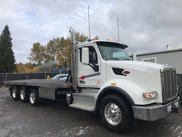 A white flatbed truck is parked in a parking lot.