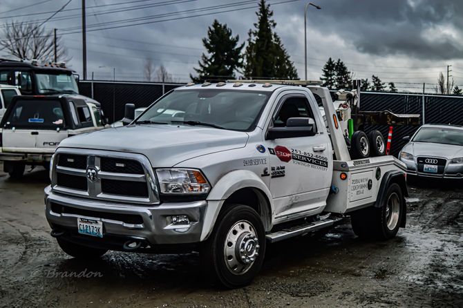 A white tow truck is parked in a parking lot.