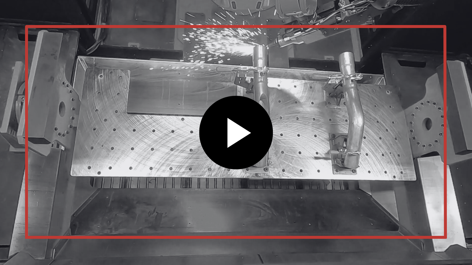 Grayscale industrial machine interior with a red outlined rectangle and a play button overlay center.