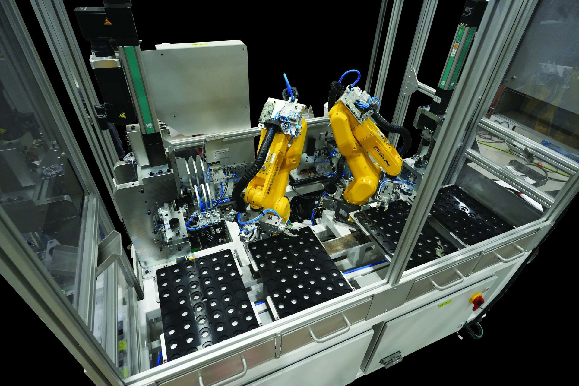 Robotic arms in an automated factory cell handling parts on a conveyor line