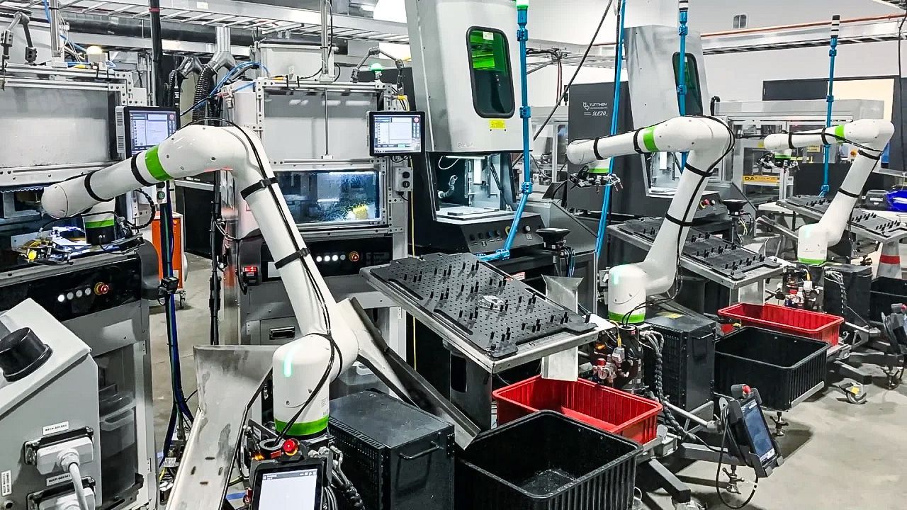Robotic arms assembling parts in a busy factory line with bins and monitors