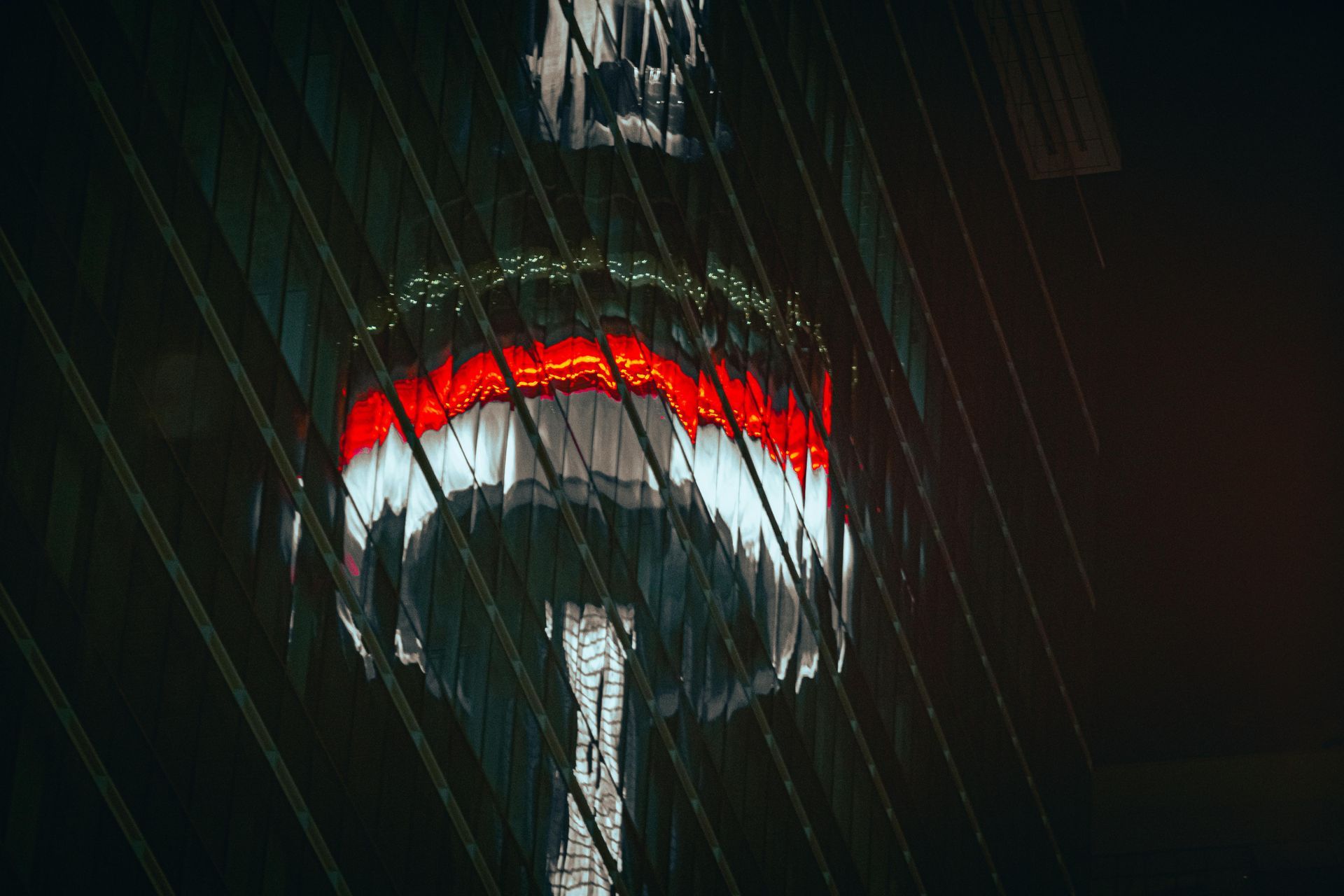 Illuminated tower observation deck at night with red and white lights in heavy rain