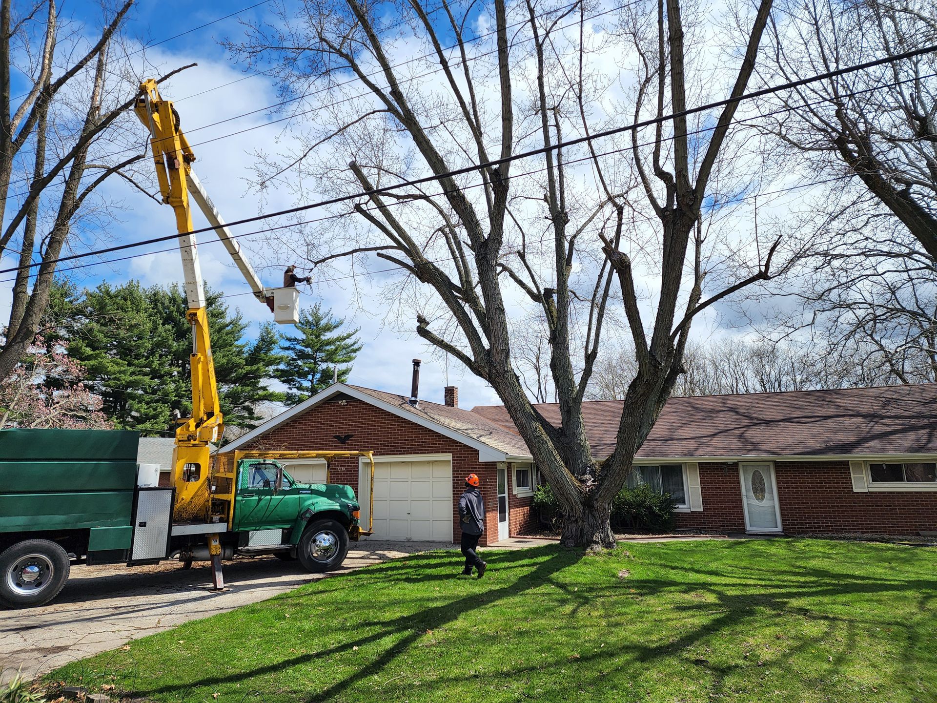 A tree trimming truck is parked in front of a house.