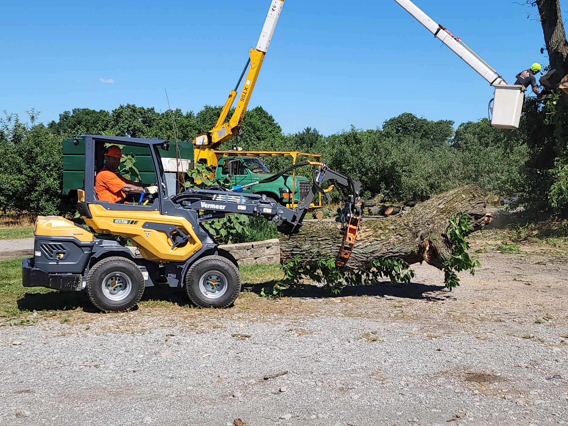 A man is driving a tractor with a crane attached to it.