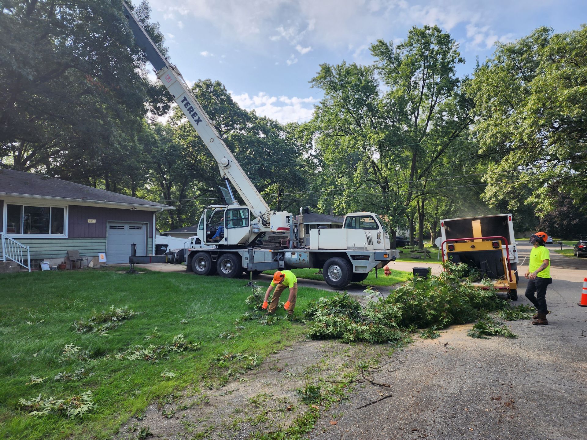 A crane is cutting a tree in front of a house in Lake Station, IN