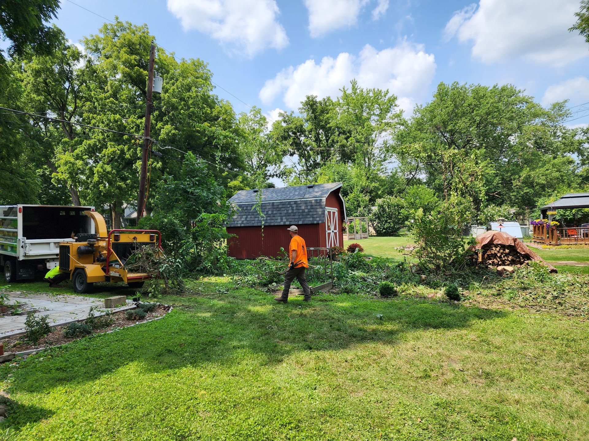 A man is walking in a yard next to a tree chipper.