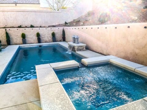 A swimming pool with a hot tub next to it