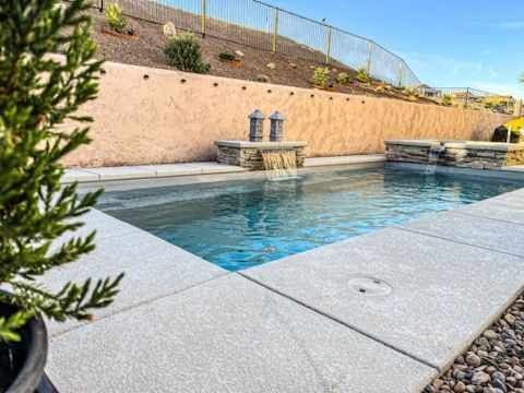 A large swimming pool with a waterfall in the backyard of a house.