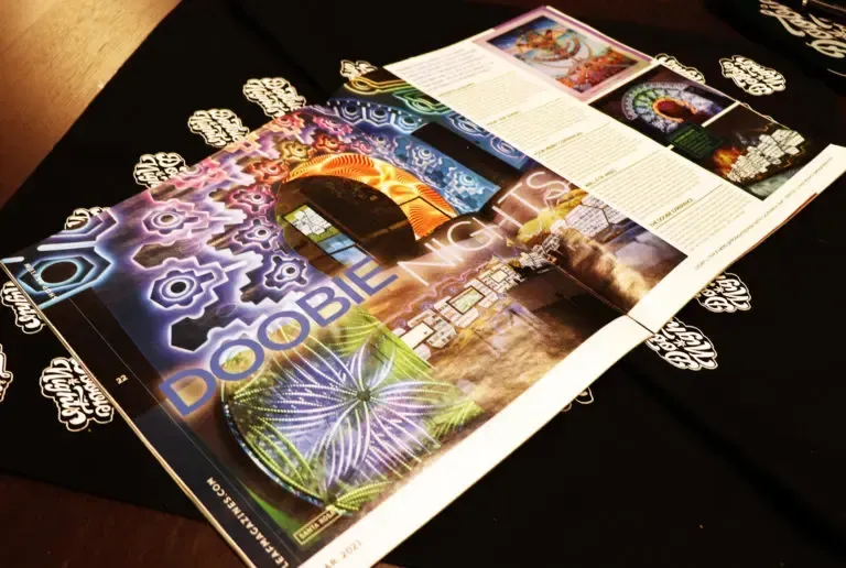 Magazine open on a black fabric with white decorative patterns.  The cover features colorful graphic designs.