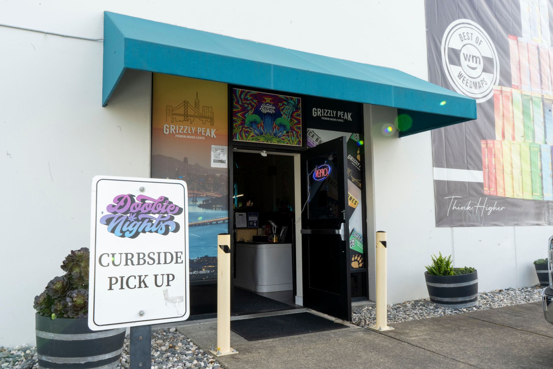 A tent with a banner advertising curbside pickup. The business is located in front of a building with a blue awning.