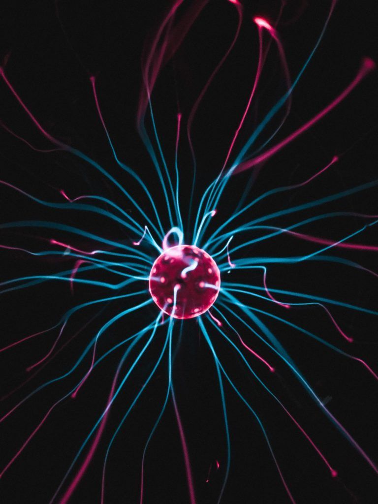 Red and blue electric plasma ball with tendrils radiating outward against a black background.