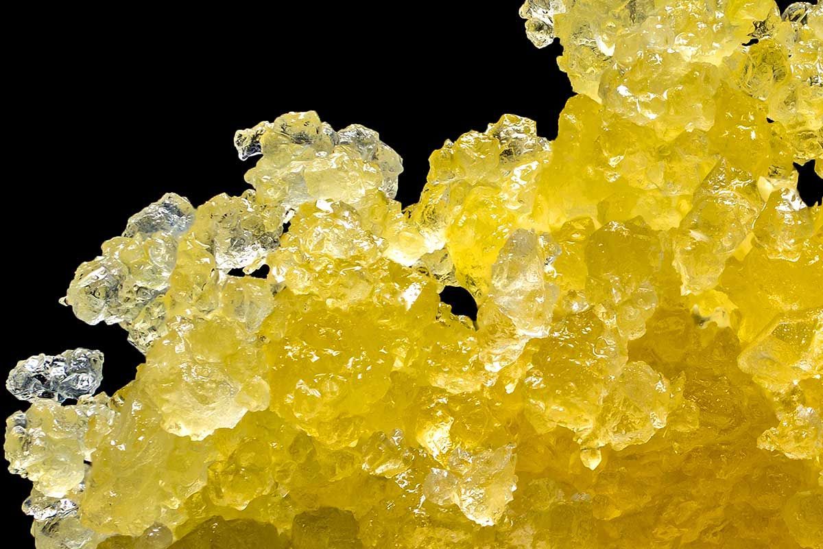 A close up of golden live resin diamonds piled up against a black background.