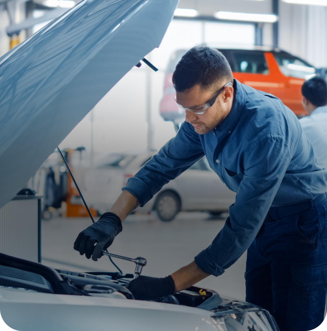 Mechanic in blue coveralls inspecting a car engine in a repair shop with the hood open | A1 Brake & Service