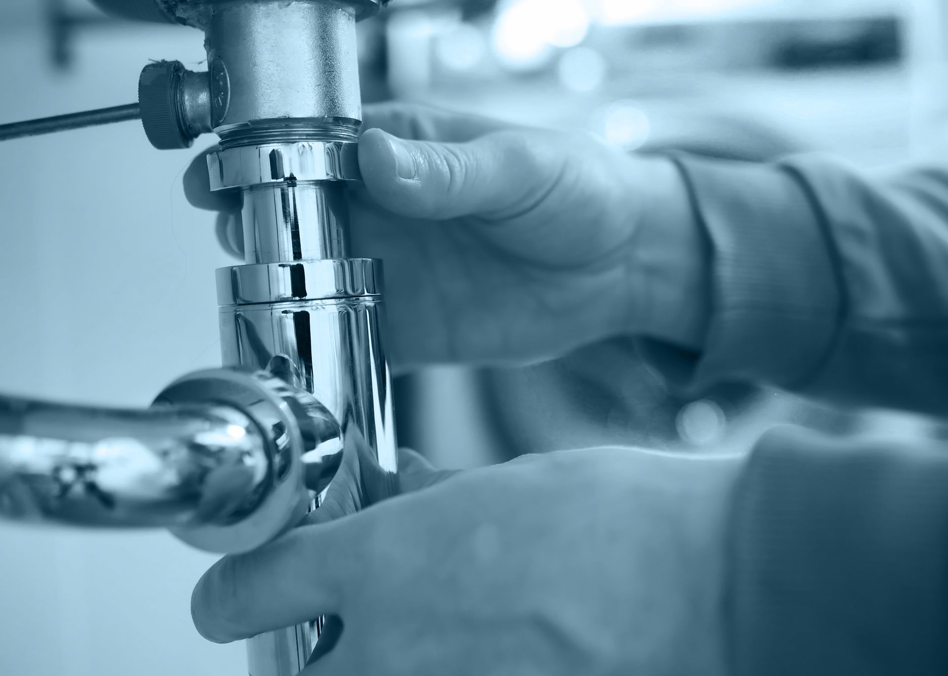 A plumber is fixing a sink pipe with a wrench.