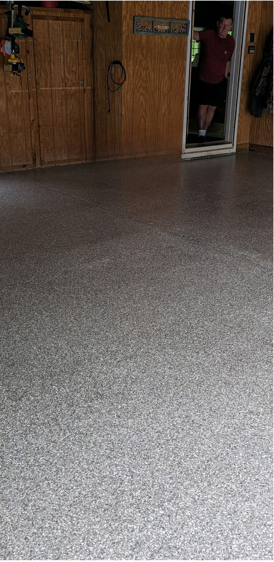 Speckled gray floor in front of wooden doors, with a person partly visible in the doorway.